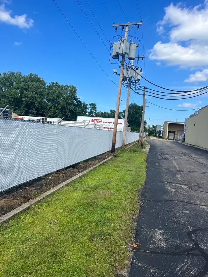 White chain link fence with privacy inserts along a drive